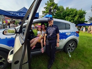 radiowóz obok policjantka ,a za kierownicą kobieta z dzieckiem na kolanach
