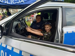dziecko siedzące za kierownicą radiowozu, obok policjantka