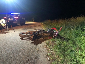 motocykl leżący na jezdni, w tle radiowóz z sygnałami świetlnymi