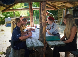 policjantka, strażacy i inne osoby z obozu harcerskiego siedzą przy stole