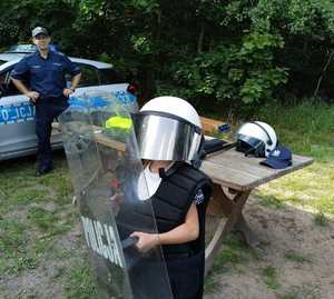 dziecko w policyjnym kasku i z policyjną tarczą w tle policjant