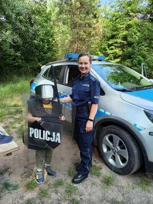 dziecko w policyjnym kasku i z policyjną tarczą stojące z policjantką