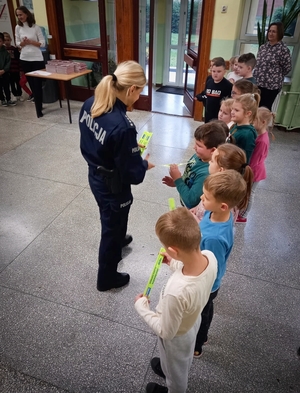 policjantka wręcza odblaski dzieciom